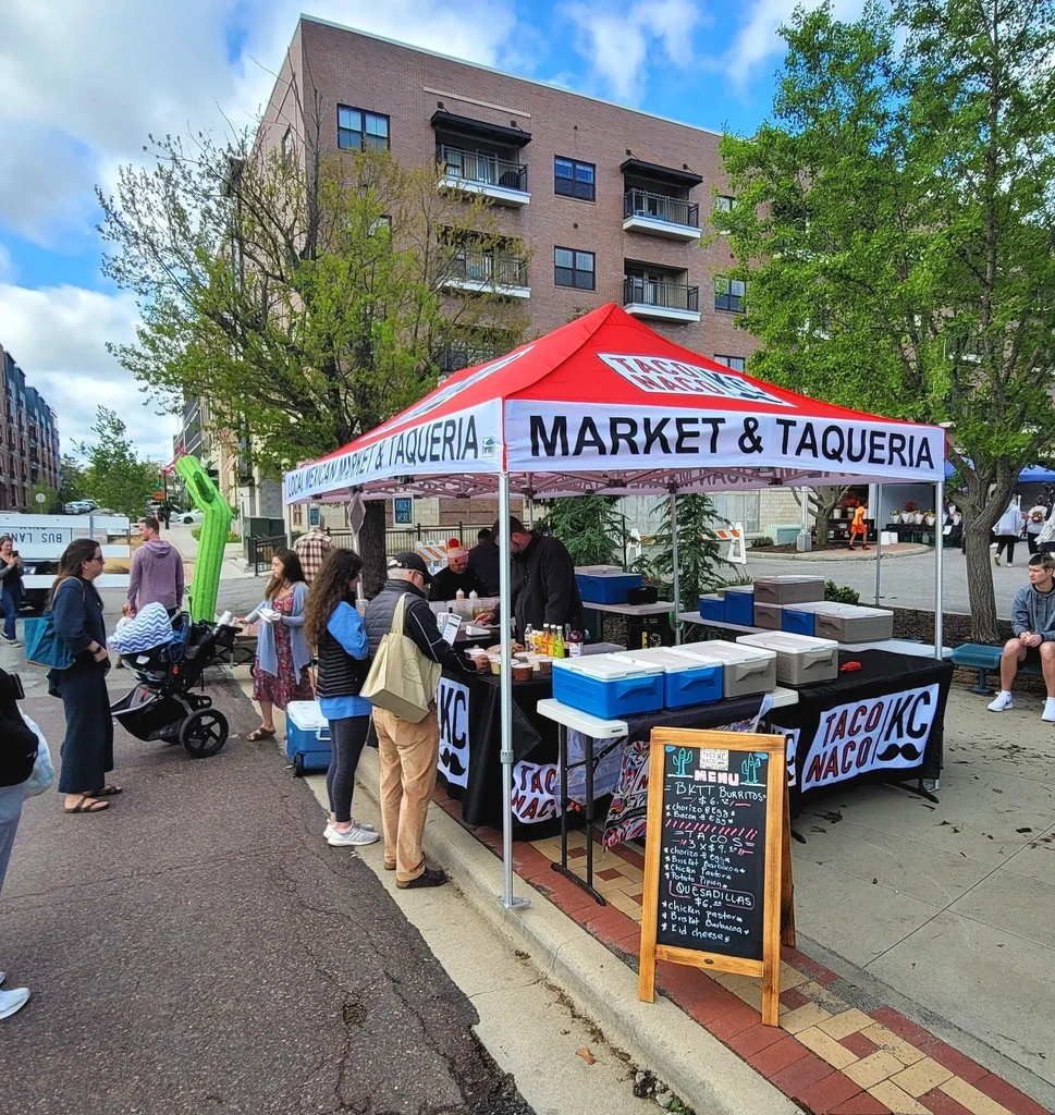 Lively outdoor Mexican food market with vendors serving customers.