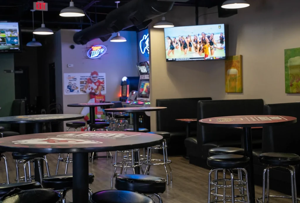 Interior of an empty sports bar with Chiefs tables, TVs, and arcade games.