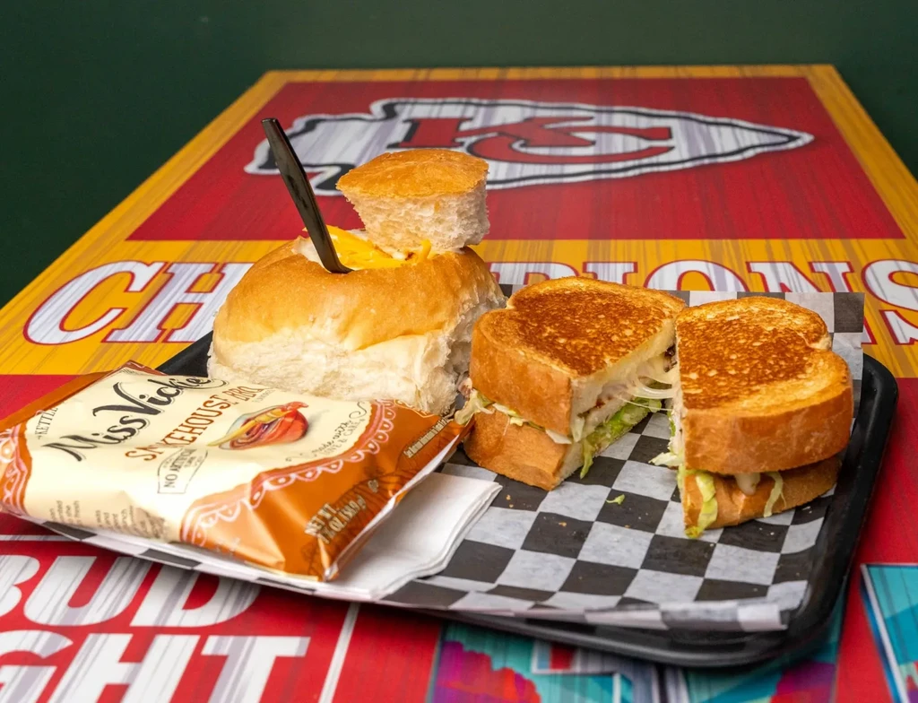 Chili bread bowl, grilled sandwich, and chips on a Chiefs-themed tray.