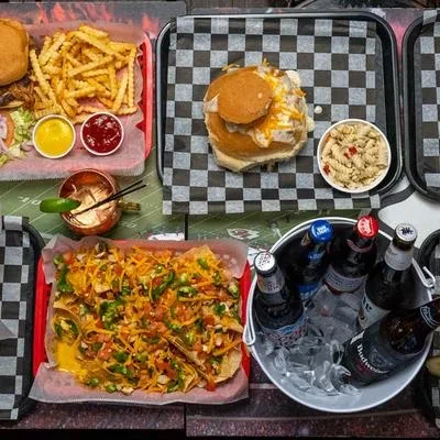 Overhead: burgers, loaded nachos, fries, beers, and a cocktail.