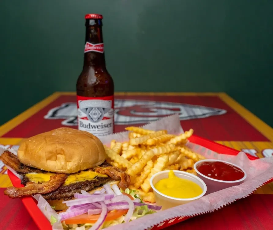 Double burger, fries, salad, and cold Budweiser beer with condiments.