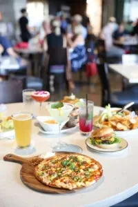 Pizza, burger, beer, and cocktails on a restaurant table.