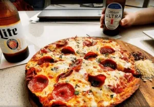 Pepperoni pizza with Miller Lite and Michelob Ultra beers on a board.