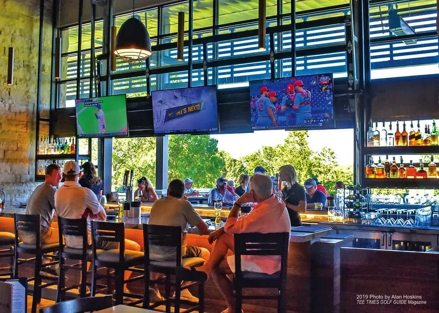 Lively bar with patrons, sports on TVs, and outdoor views.