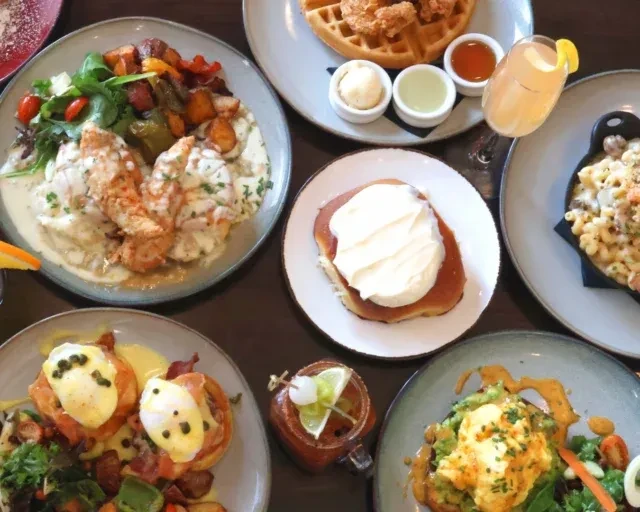Overhead view of a diverse brunch table with gourmet food and cocktails.