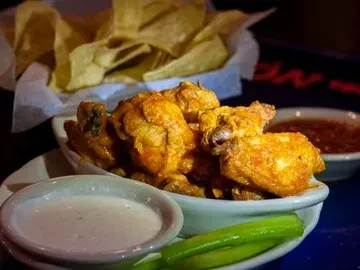 Golden, crispy chicken wings with dip, celery, and tortilla chips.