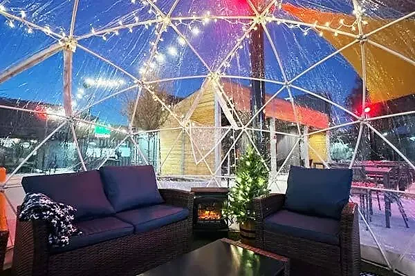 Heated igloo dome with sofas, string lights and fireplace