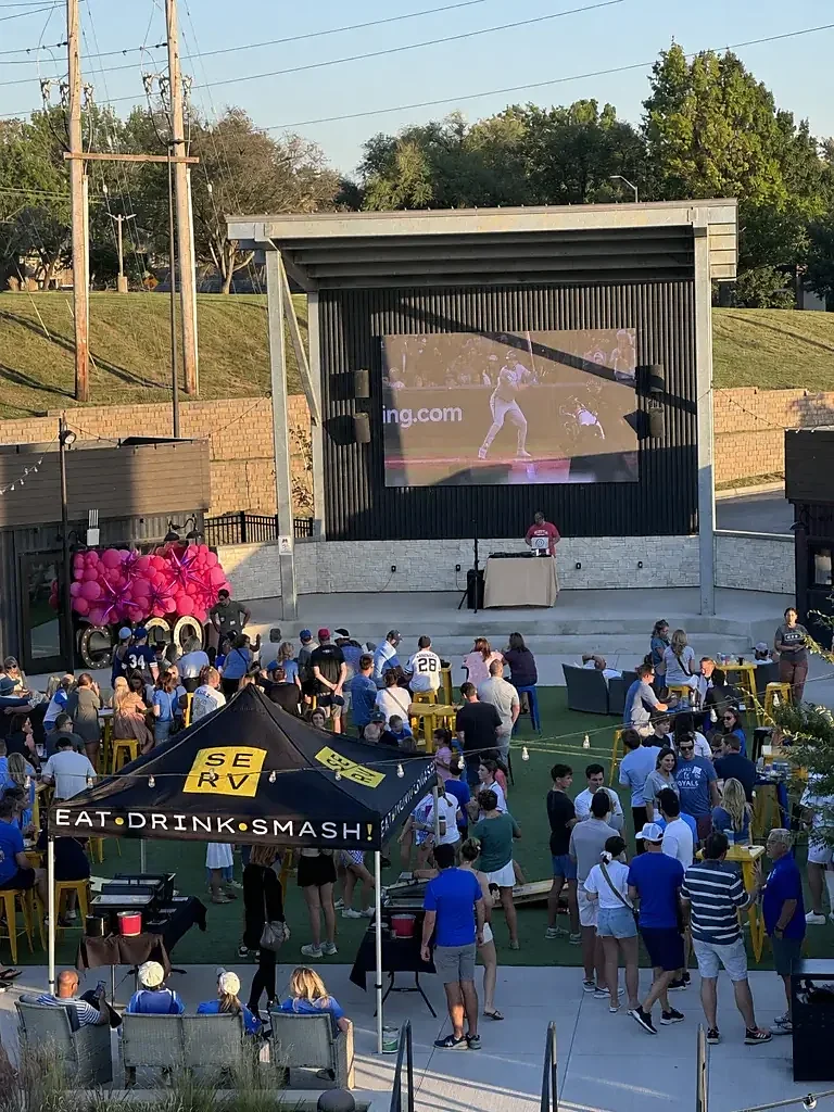 Outdoor courtyard crowd watching baseball on large video board