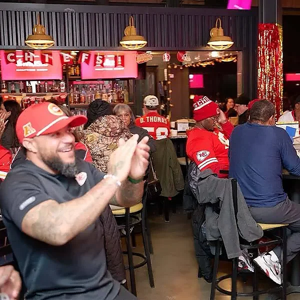 Guests in Chiefs gear watching a game at indoor bar