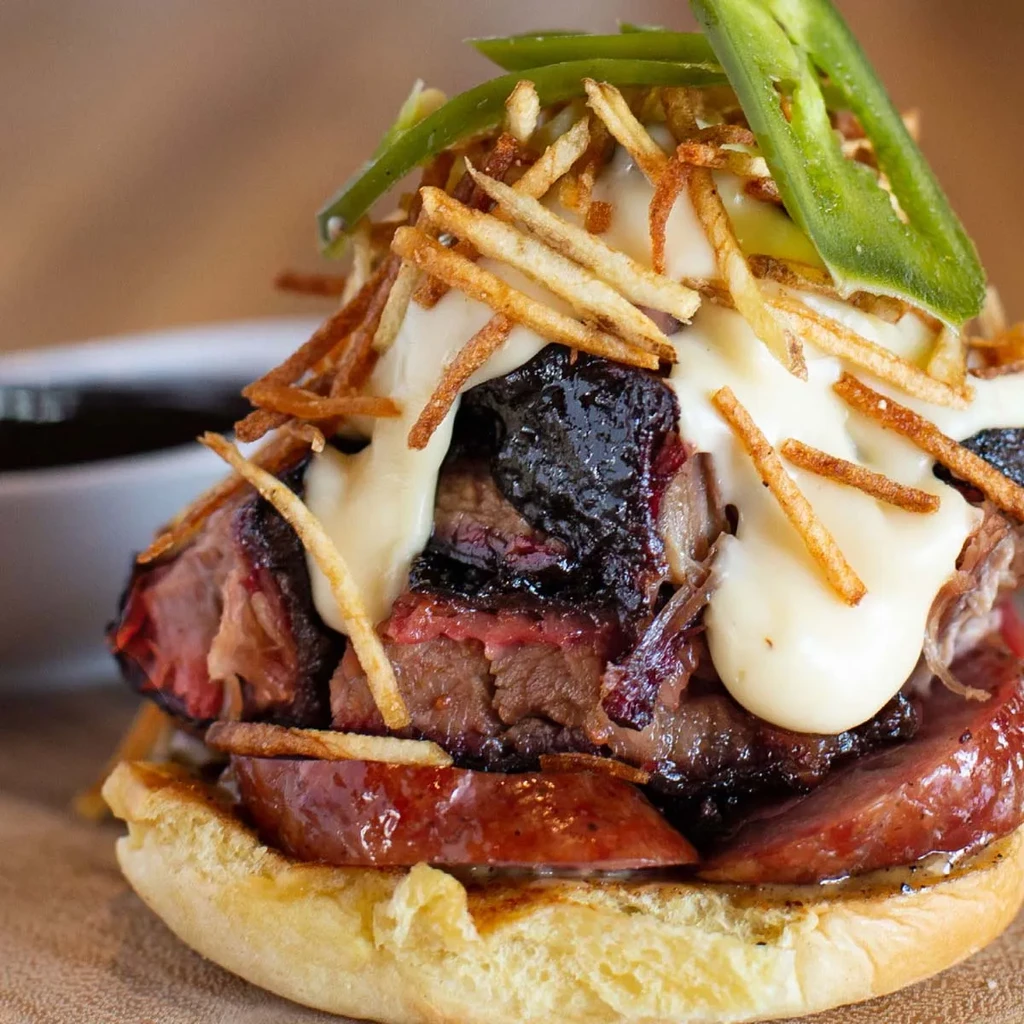 Dark meat and sausage sandwich with sauce, shoestring fries, jalapeños.