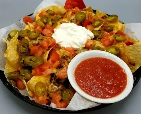 Large nachos loaded with cheese, beef, tomatoes, jalapeños, sour cream, and salsa.