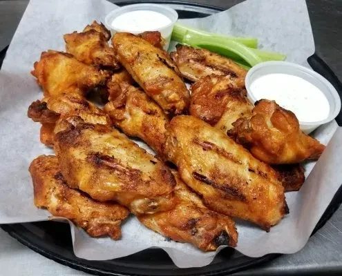 Crispy golden-brown chicken wings with dipping sauce and celery sticks.