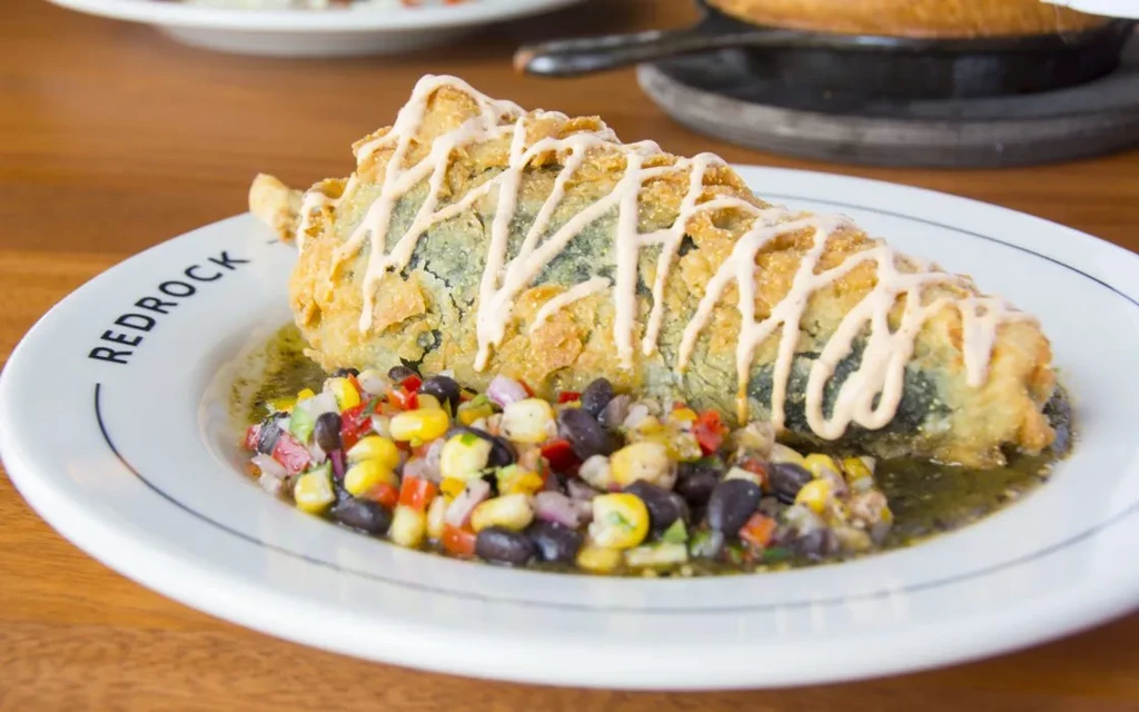 Crispy golden-brown fried chili relleno with sauces and corn-bean salsa.