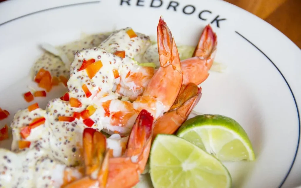 Cooked shrimp with creamy mustard sauce, red bell peppers, and lime.