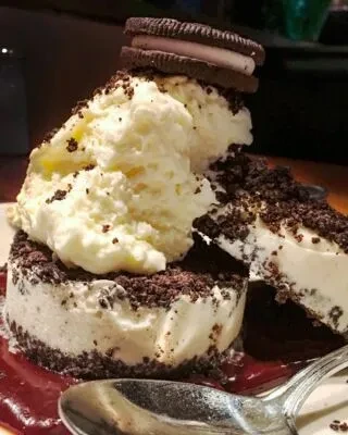 Layered Oreo ice cream dessert with vanilla scoops and red sauce.