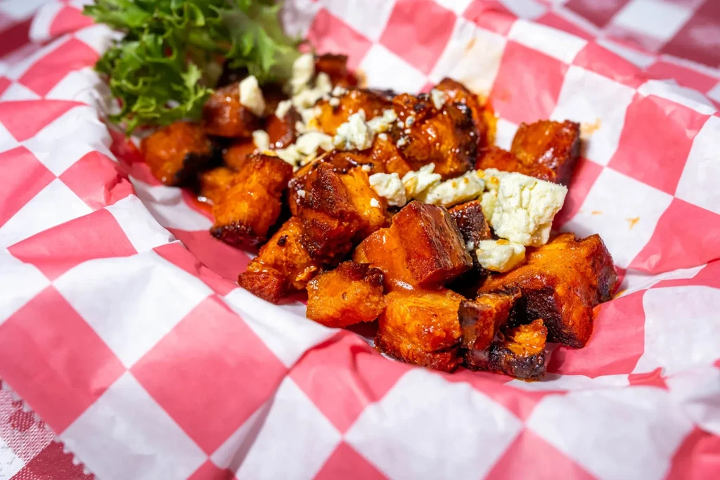 Roasted sweet potato cubes with red sauce, crumbled cheese, and lettuce.