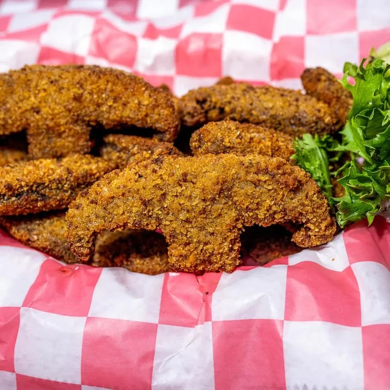 Basket of golden-brown fried pickles or mushrooms with lettuce.