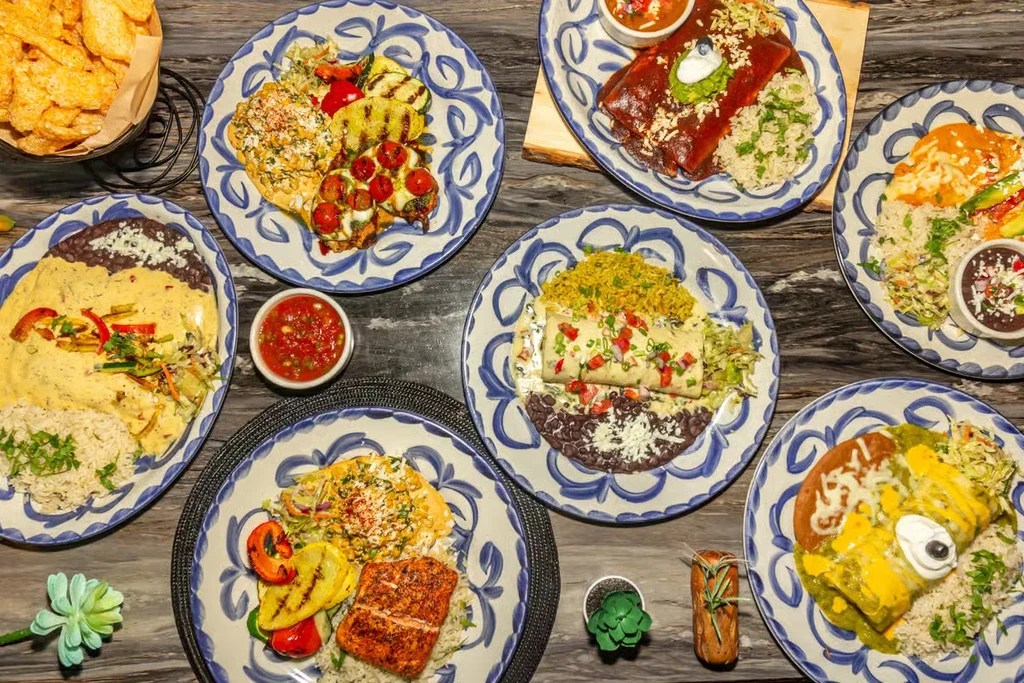 Table laden with colorful Mexican and Latin American food dishes.