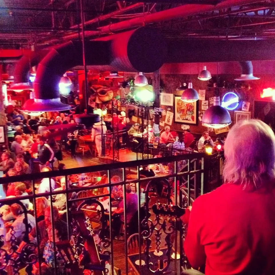Elevated view of a red-lit, multi-level restaurant filled with patrons.