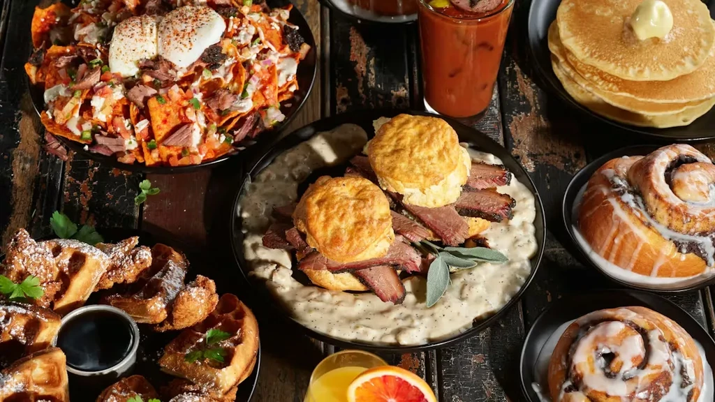 Overhead shot: Rustic table with diverse breakfast/brunch food and drinks.