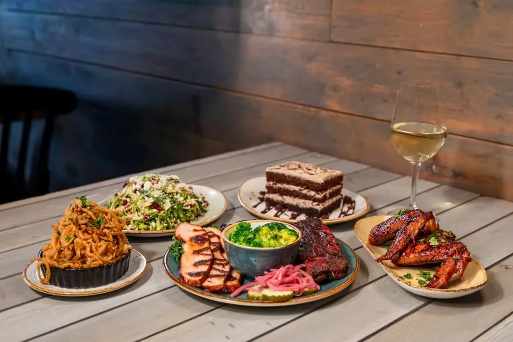 Well-composed meal spread with meat, salad, cake, and white wine.