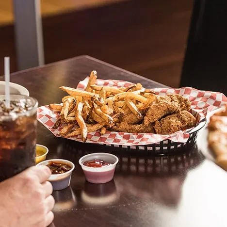 Basket with crispy fried chicken/fish, french fries, and dipping sauces.