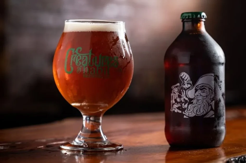 Chilled amber beer in glass and bottle with unique labels on wood.