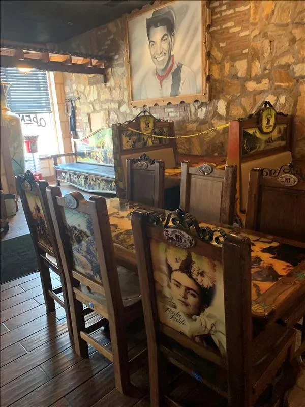 Restaurant interior: rustic stone walls, Pedro Infante art, Frida Kahlo chairs.