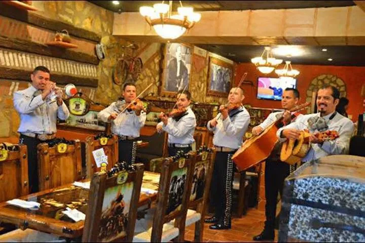 Six male mariachi musicians performing in a restaurant.