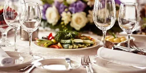Elegantly set dining table with empty wine glasses and fresh vegetables.