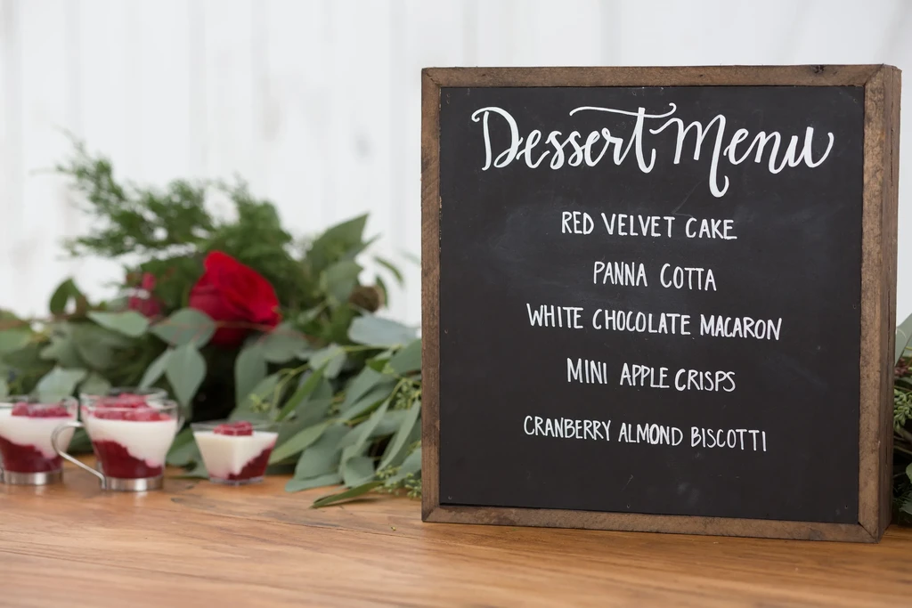 Rustic chalkboard dessert menu, small desserts, greenery, and a red rose.