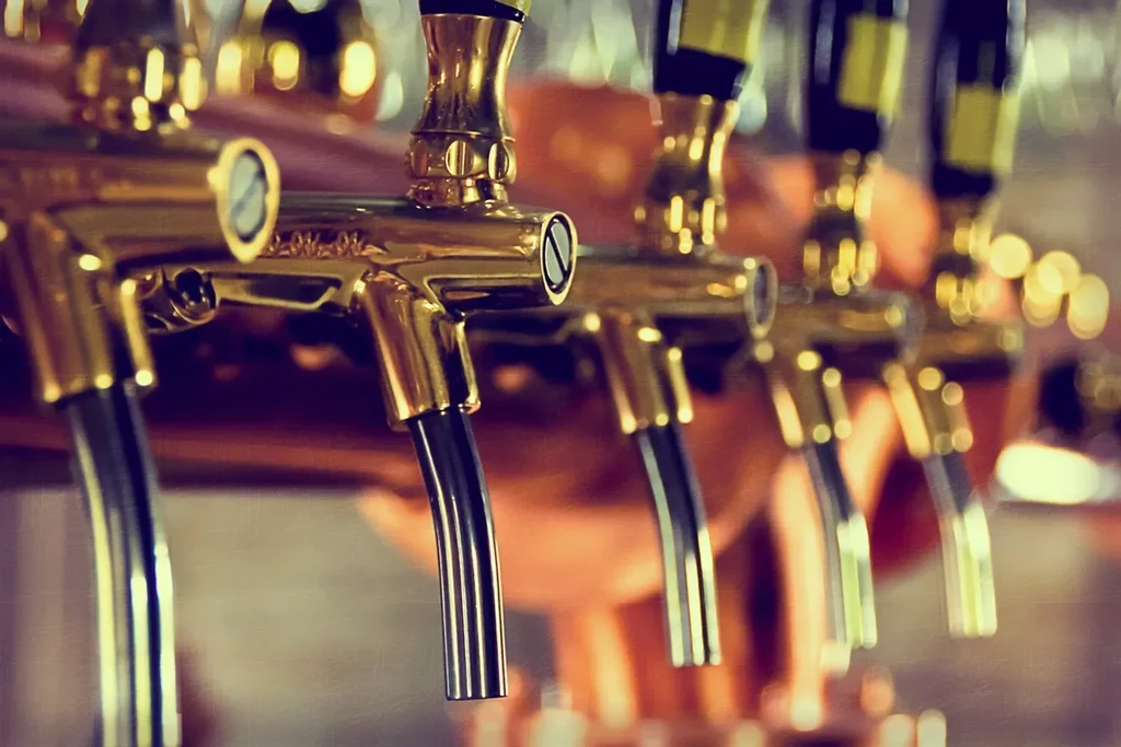 Close-up of golden beer taps with warm, blurred background.