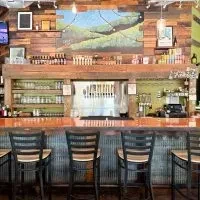 Rustic wooden bar with beer taps and a painted mountain mural.