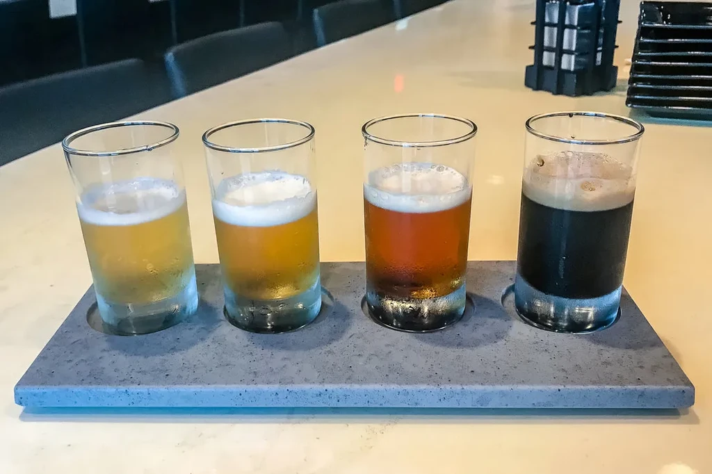Four cold beer tasters on a tray, from light to dark.