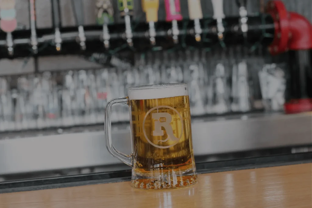 Beer mug with 'R' logo on a bar counter with taps.