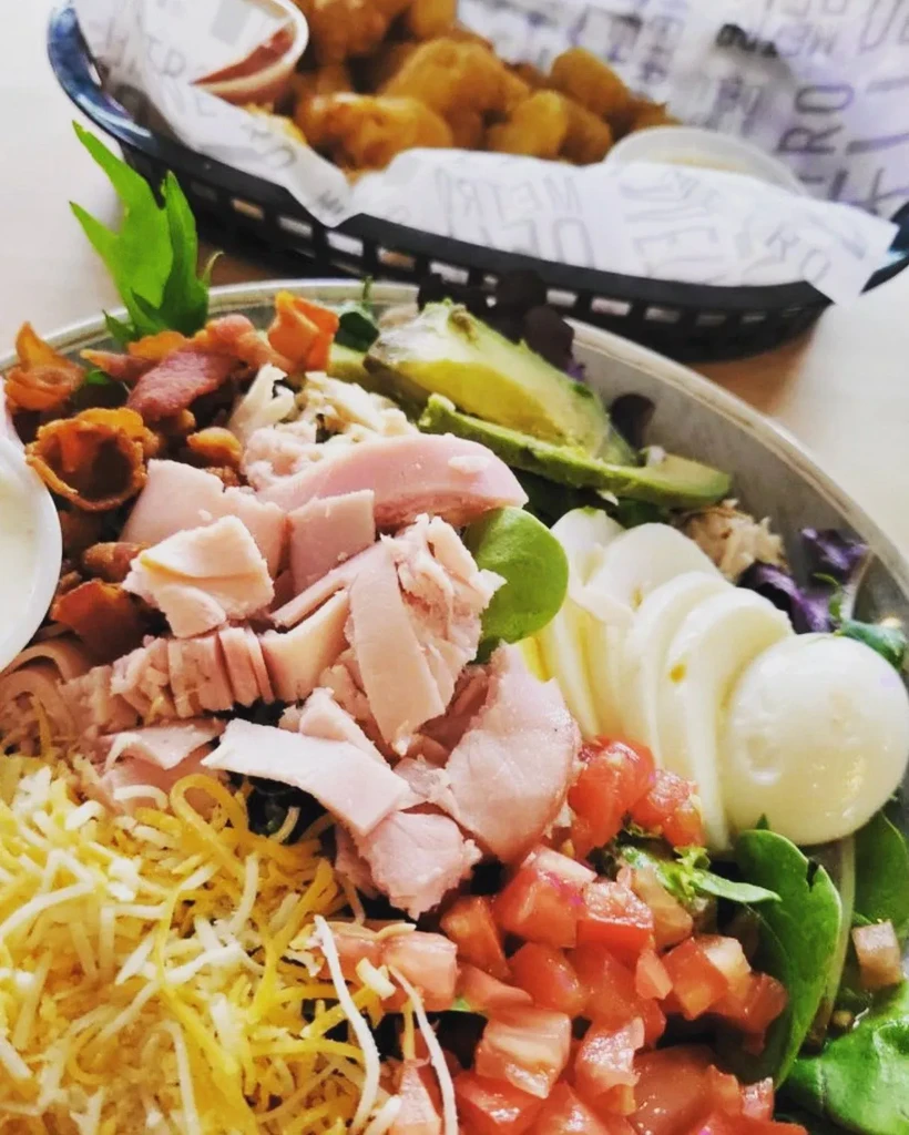 Generous chef salad with avocado, eggs, and fried sides.