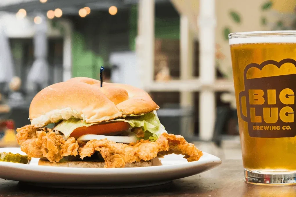 Close-up of a fried chicken sandwich and Big Lug Brewing Co. beer.