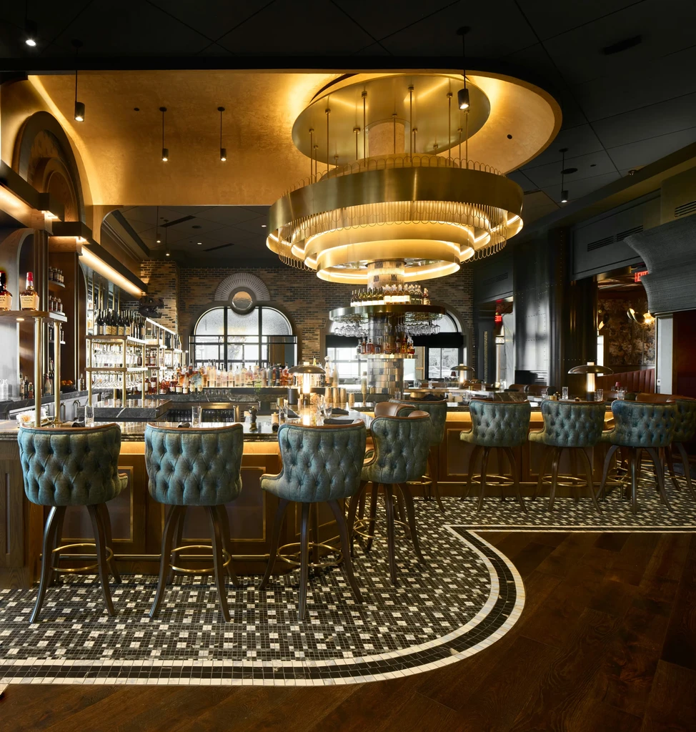 Elegant bar interior with dark wood, teal stools, mosaic floor, and chandelier.