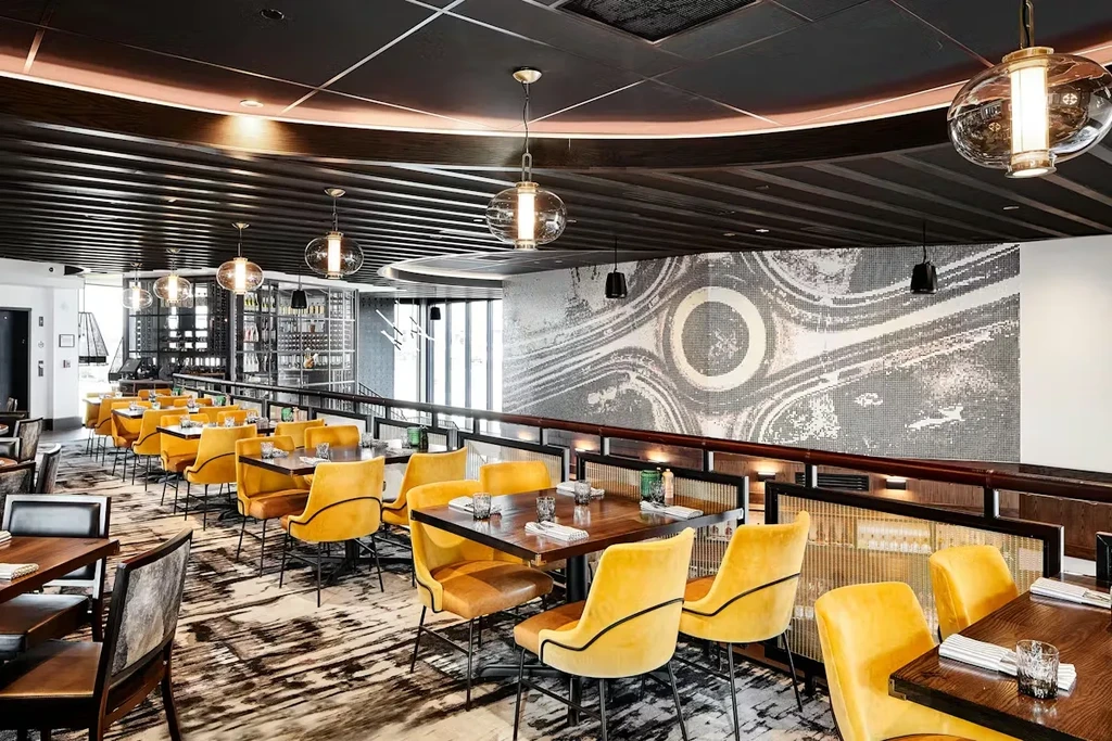 Empty modern restaurant interior with yellow velvet chairs and abstract mural.