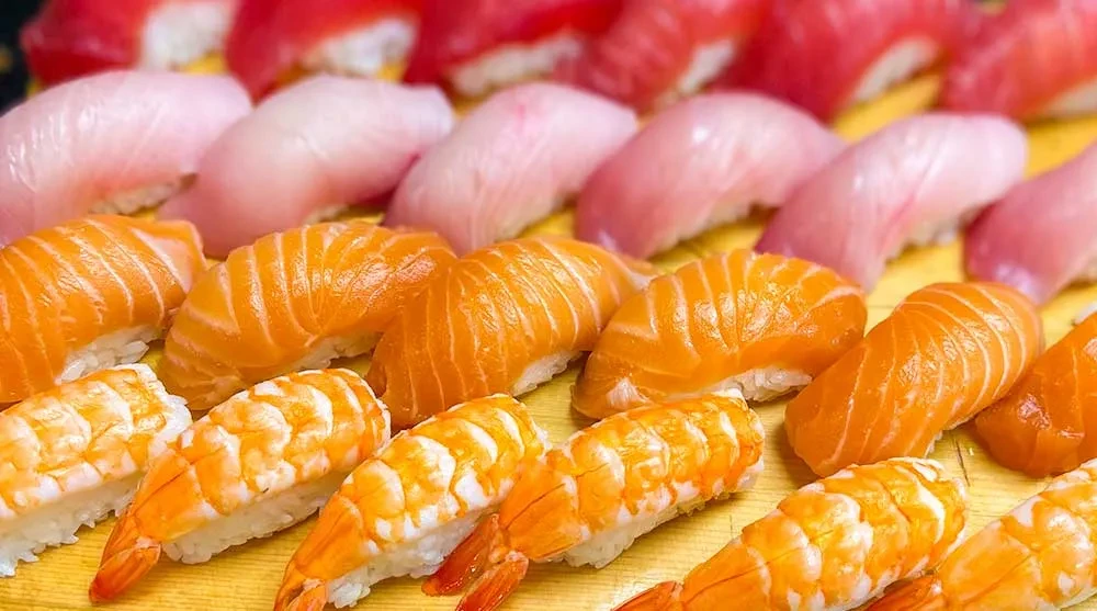 Rows of shrimp, salmon, and tuna nigiri sushi.