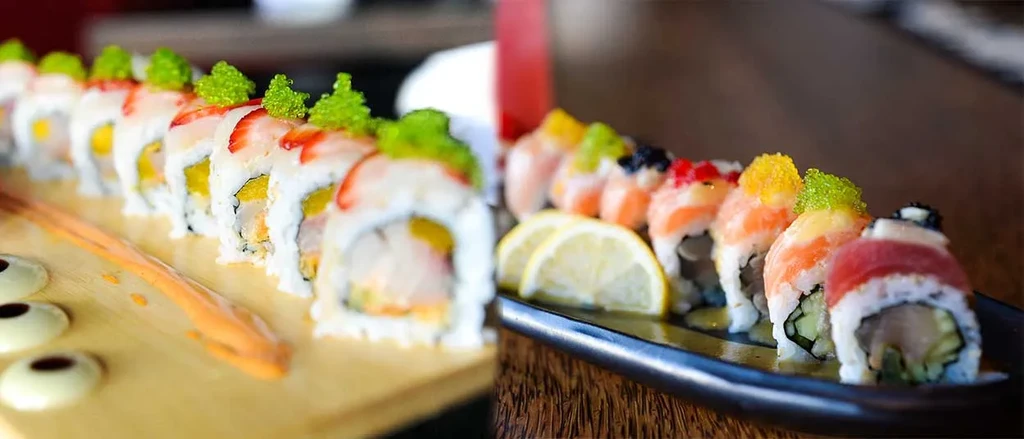 Two distinct platters of sushi rolls: one with strawberries, one with fish.