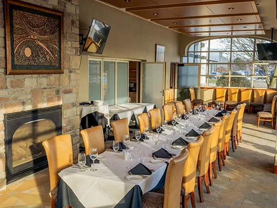 Empty elegant restaurant dining room with long table and stone fireplace.