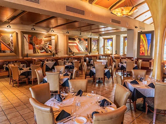 Elegant, empty upscale restaurant dining room with stained-glass windows and abstract art.