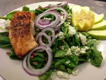 Grilled salmon salad with greens, blue cheese, pecans, apple, and lemon.