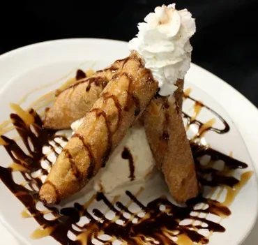 Three fried pastries with whipped cream, ice cream, chocolate, caramel sauce.