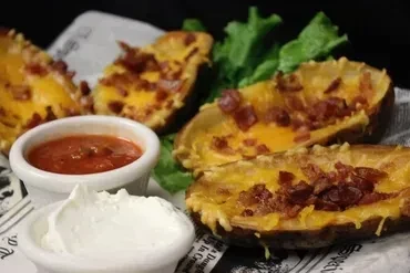 Close-up of cheese and bacon potato skins with salsa and sour cream.