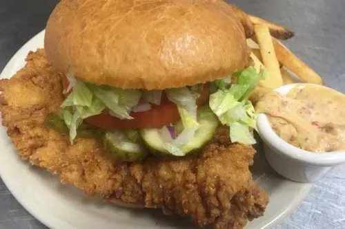 Crispy fried chicken sandwich, lettuce, tomato, pickles, fries, and dipping sauce.