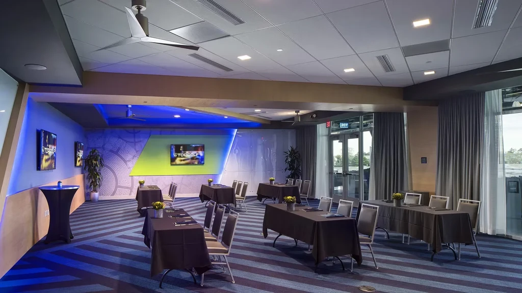 Empty modern Topgolf event room with blue lighting and distinctive striped carpet.