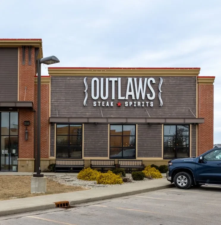 Modern rustic OUTLAWS STEAK ★ SPIRITS restaurant exterior with dark wood.