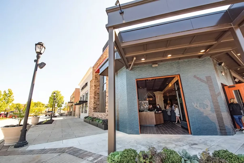 Teal brick restaurant entrance with subtle deer silhouette, people visible.